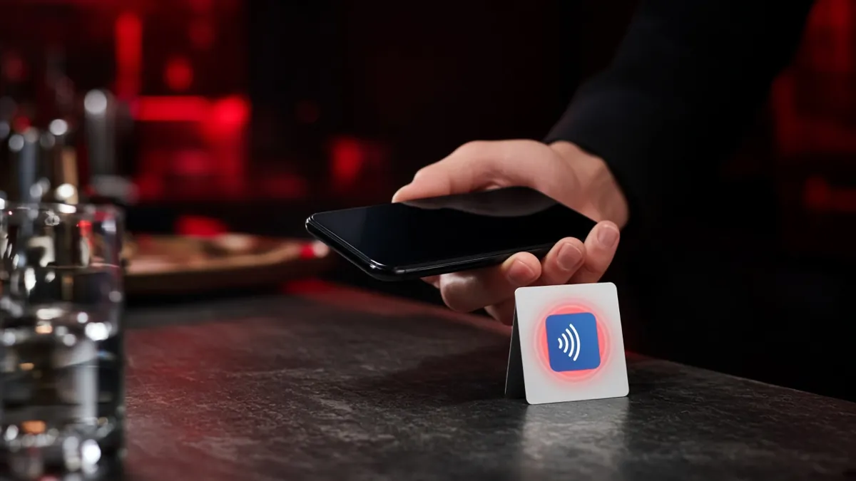 A customer tapping a phone on an NFC review card standing on a counter